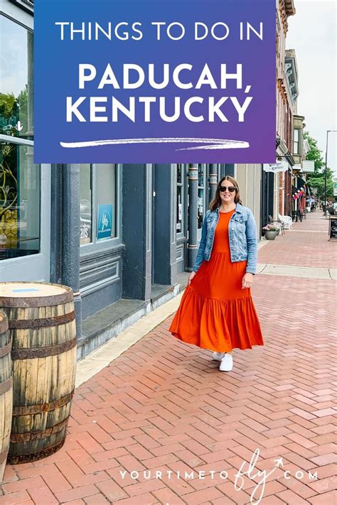 A Woman In An Orange Dress Is Walking Down The Street With A Sign That