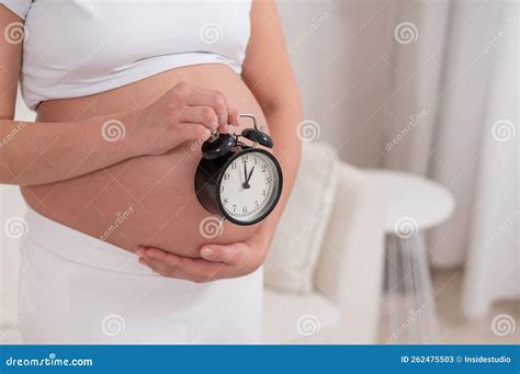 A Pregnant Woman With A Naked Belly Holds An Alarm Clock Intended Date Of Birth Stock Image