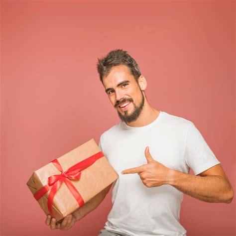 Hombre Sonriente Que Sostiene La Caja De Regalo Que Se Ala El Dedo