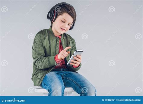 Menino De Sorriso Nos Fones De Ouvido Que Sentam Se No Tamborete E Em