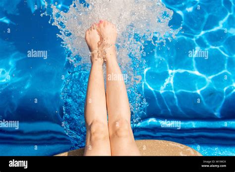 Legs Of Young Fit Female Splashing Water While Spending Time In