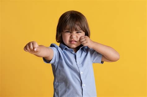 아이의 분노와 감정 화가 난 오렌지 스튜디오 배경을 느끼는 카메라에 주먹을 보여주는 분노 어린 소년 프리미엄 사진