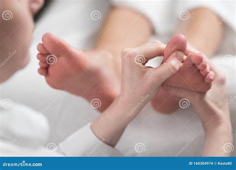 Professional Female Masseur Giving Reflexology Massage To Woman Foot