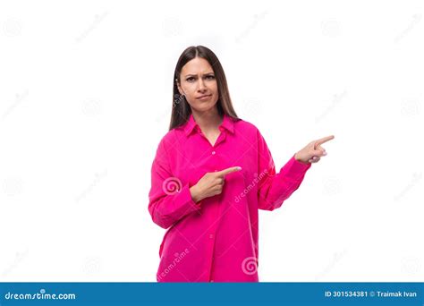 Jovencita Guapa De Brunette Vestida Con Puntos De Camisa Rosa Brillante Con Las Manos En Una