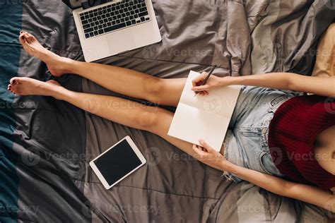 Gros Plan D Une Jeune Femme Crivant Dans Un Livre Assise Sur Son Lit