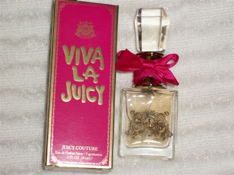 A Bottle Of Perfume Sitting Next To A Pink Box With A Red Bow On It