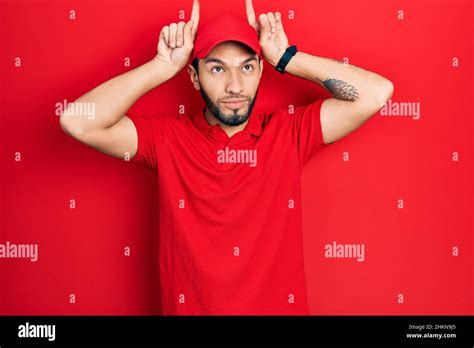 Hispanic Man With Beard Wearing Delivery Uniform And Cap Doing Funny