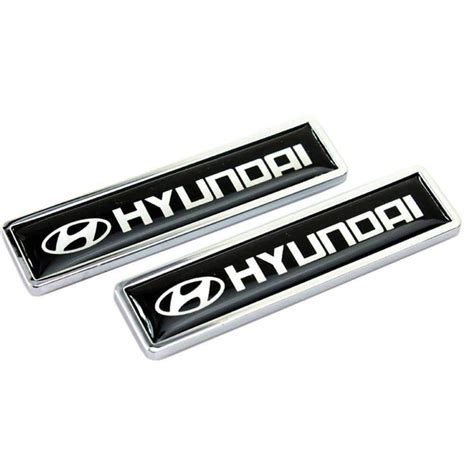 Two Chrome And Black Toyota Emblems On White Background