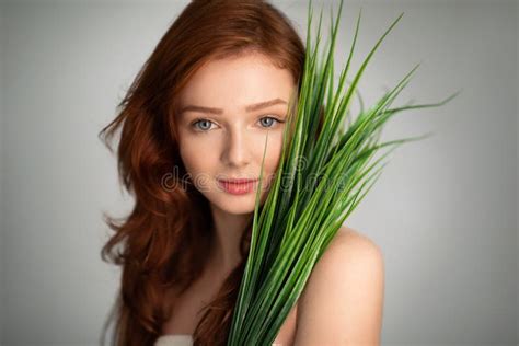 Pretty Ginger Haired Girl Posing With Green Plant Leaves Gray