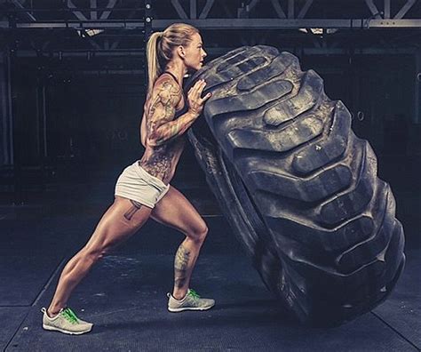 A Woman Pushing A Large Tire In A Gym