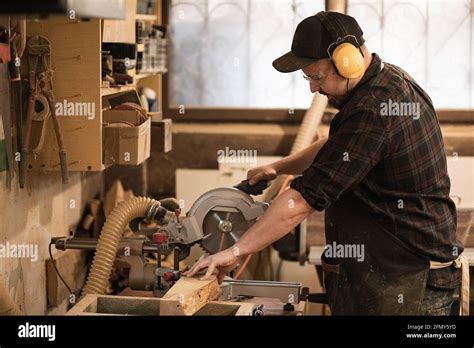 Carpenter Cutting Wood On Circular Saw In Workshop Place Stock Photo