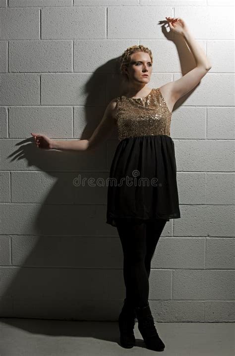 La Femme Blonde Grande Se Penche De Retour Contre Un Mur Blanc De Cinderblock Image Stock