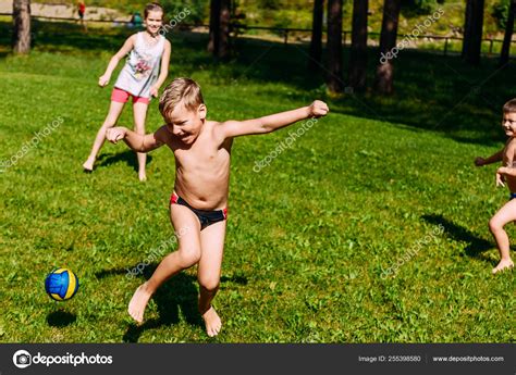 Children playing dodgeball with the ball on the green lawn in the ...