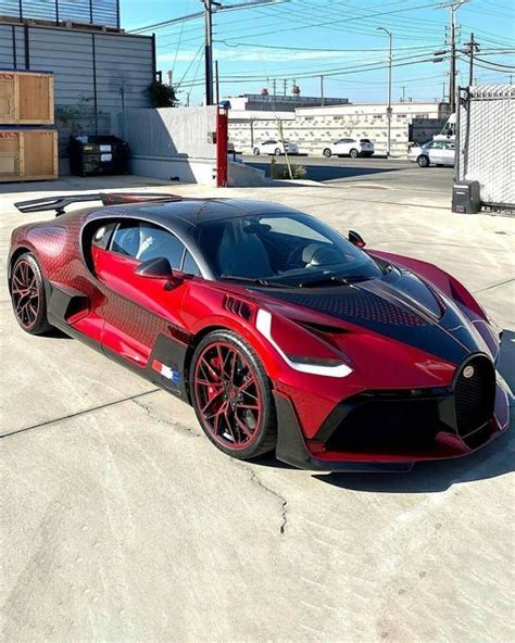 A Red And Black Bugatti Is Parked In The Parking Lot Next To A Building