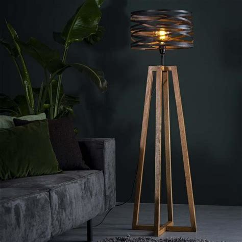 A Lamp That Is On Top Of A Wooden Tripod In Front Of A Couch