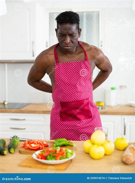 Focused Half Naked Man Tying Red Apron While Getting Ready To Cook