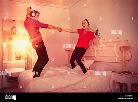 Playful Couple Dancing On Bed Listening To Music With Mp3 Players And