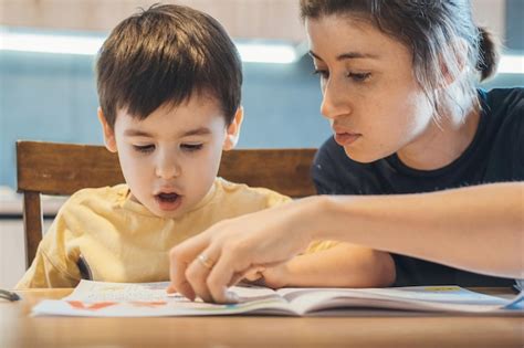 Madre Ayudando Con La Tarea A Su Hijo Se Alando Algo Escrito En Su