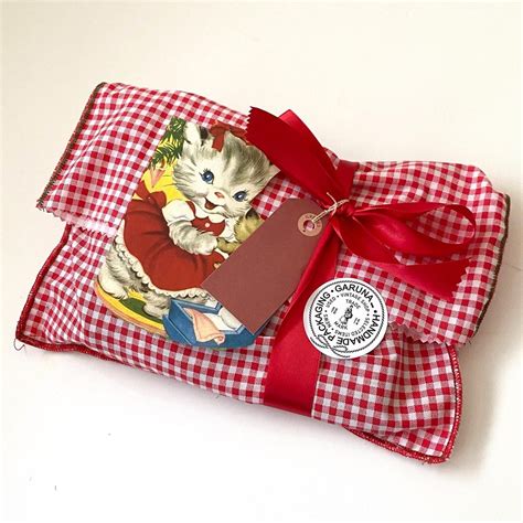 A Red And White Checkered Bag With A Kitten On It S Side Tied To A Ribbon