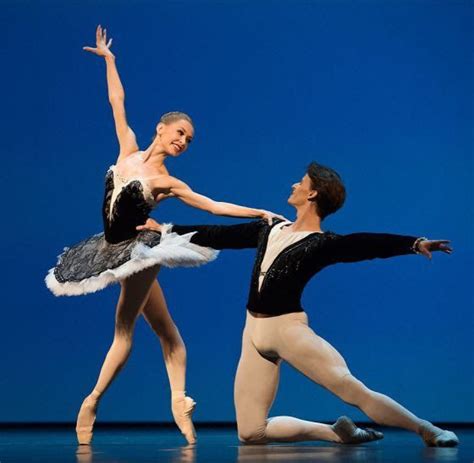 Two Ballerinas In Black And White Tutus One Holding The Other S Leg