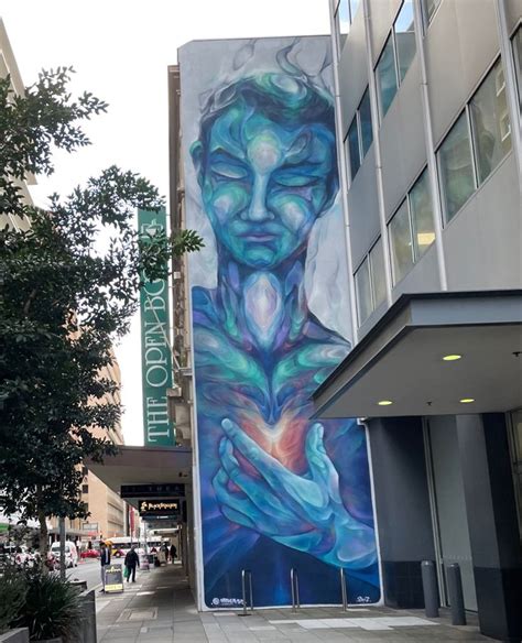 A Large Mural On The Side Of A Building With A Woman Holding Her Hands