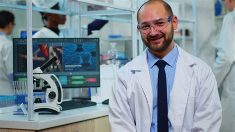 Microbiologist sitting in laboratory looking at camera in modern ...