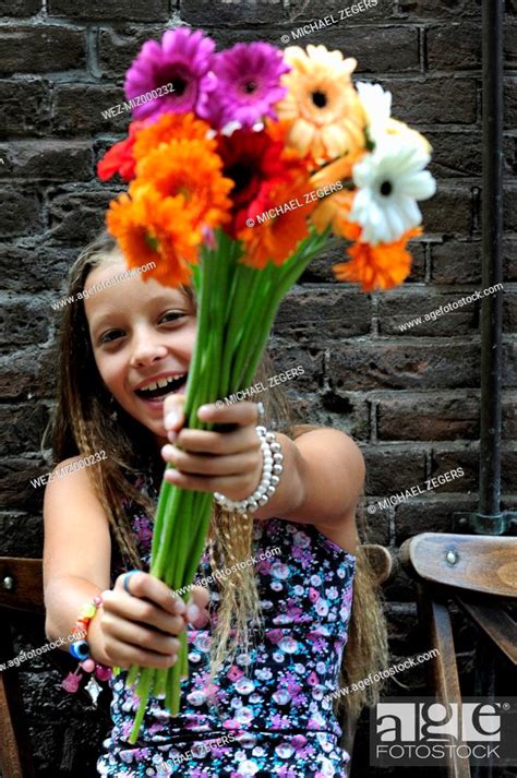 Netherlands Girl Holding Flowers In Front Of Brick Wall Smiling