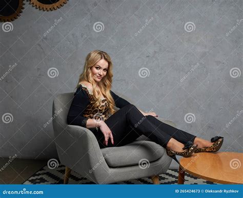 Portrait Of Beautiful Blonde Woman In Black Suit Sitting On In Classic Interior Stock Image