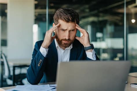 Empresario deprimido de mediana edad mirando la computadora portátil y