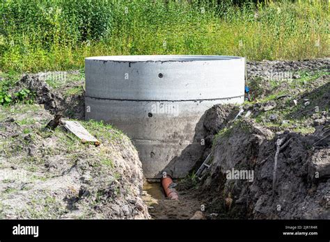 Concrete Septic Tank Made Of Several Rings With An Orange Drainpipe At