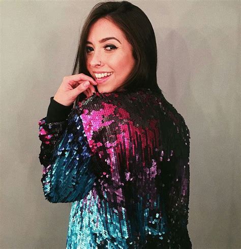 A Woman In A Colorful Sequin Top Posing For A Photo With Her Hand On