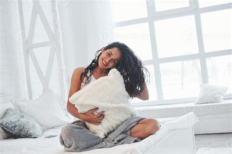 Nice Sincere Smile Brunette Having A Rest On The White Couch In Her Bedroom At Daytime