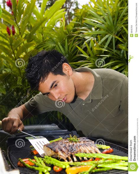 Homem Americano Que Grelha A Cremalheira De Cordeiro Foto De Stock