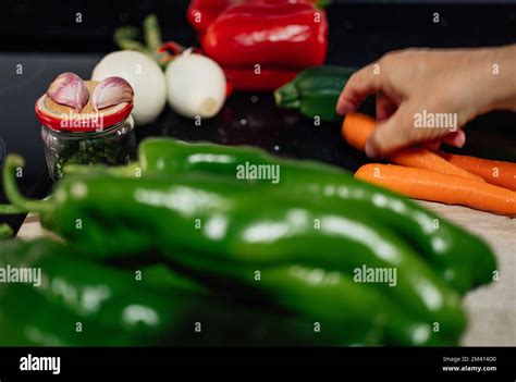 Defocused Woman Hand In Action Getting Carrot For Cooking Healthy Food