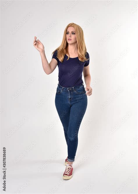 Full Length Portrait Of A Pretty Blonde Girl Wearing Casual Blue Shirt Denim Jeans And Sneakers