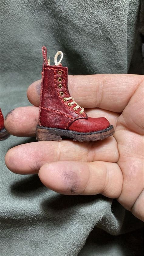 A Person Holding A Tiny Red Shoe In Their Hand