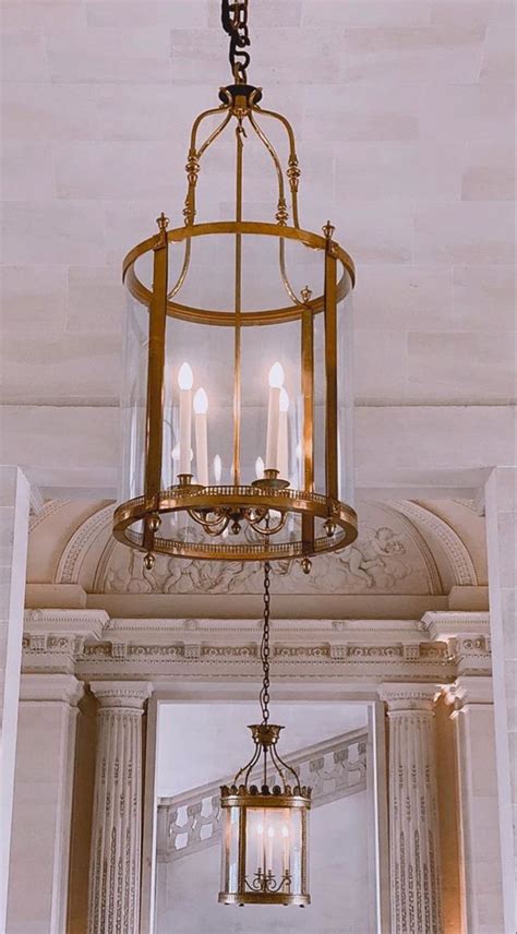 A Chandelier Hanging From The Ceiling In A Room With Columns And Arches