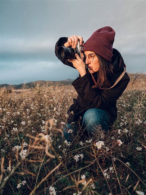 Young Woman Taking Pictures Between The Flowers At Sunset Moment By