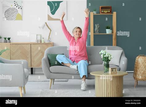 Happy Mature Woman Sitting On Sofa At Home Stock Photo Alamy