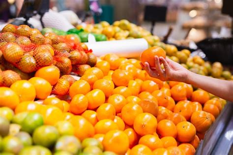 Premium Photo Woman Choosing Oranges In Grocery Store Concept Of