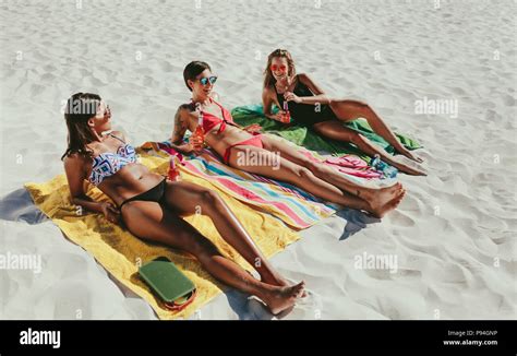 Women Relaxing On Beach With Drinks In Hand On A Sunny Day Three