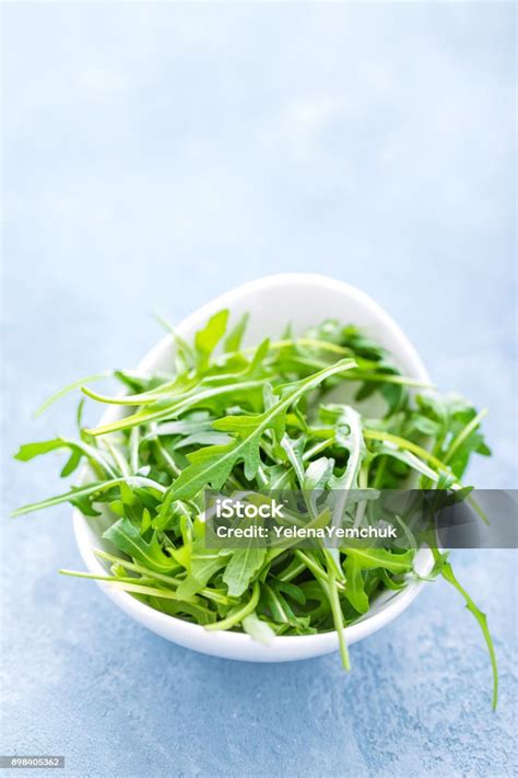 Daun Arugula Segar Dalam Mangkuk Di Atas Meja Latar Belakang Cahaya