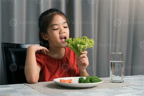 Asian little girl eating healthy vegetables with relish. 25358654 Stock ...