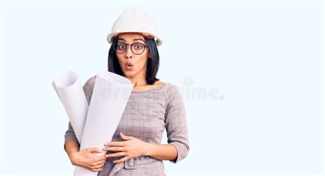 Joven Hermosa Mujer Latina Que Usa Arquitecto Hardhat Y Gafas Que Sostienen Planos Asustados Y