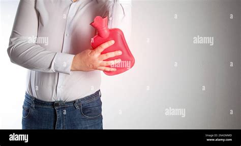 A Man On A White Background Attaches A Red Heating Pad With Hot Water To The Elbow Joint