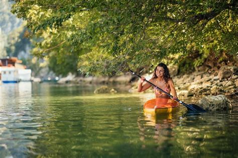 Mujer en bikini kayak en el lago durante el día soleado Foto Premium