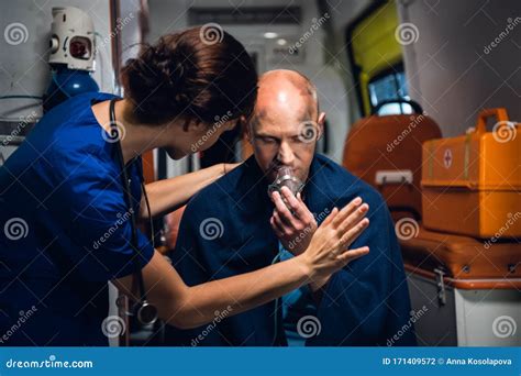 Young Woman In Uniform Stands With Man Who Sits In Oxygen Mask In