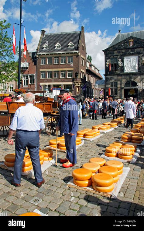 Farmer In Traditional Dress On Wooden Clogs Amongst Wheels At Cheese