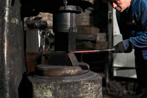 Premium Photo Blacksmith Processes A Hot Workpiece With A Power Hammer In A Workshop