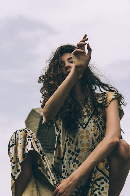 Premium Photo Low Angle Portrait Of Woman Crouching Against Sky